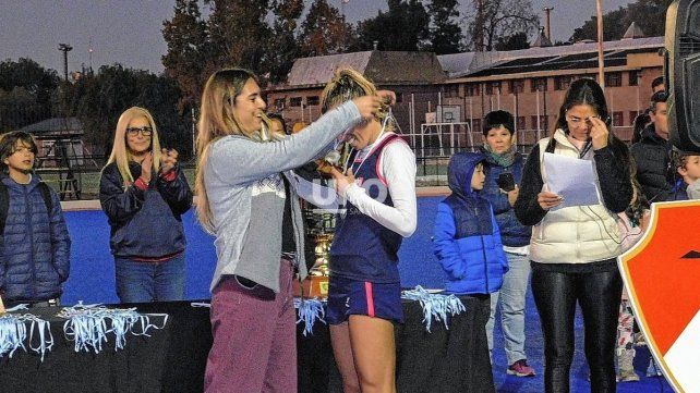 La secretaria de deportes, Florencia Molinero, le coloca a la Leona Delfina Merino la medalla por haber sido elegida la mejor jugadora de la final. 