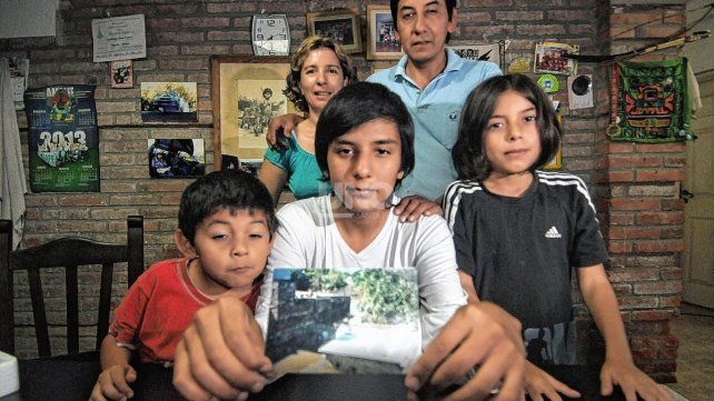2013. Atahualpa Larrea con 15 años junto a su familia, mostrando la foto de su casa inundada en 2003.