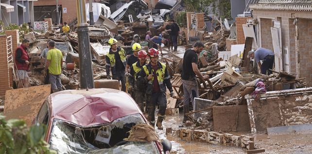 Bomberos inspeccionan el lugar mientras la gente intenta limpiar los daños causados por las inundaciones en Massanassa, en las afueras de Valencia, España, el viernes 1 de noviembre de 2024. (Foto AP/Alberto Saiz)