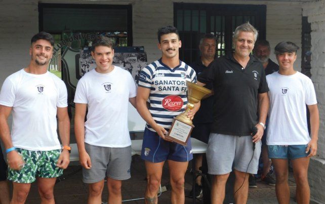 Alejandro Molinas, capitán de CRAI, recibe la copa de manos de los nietos del Toro Pelossi y el presidente de Uni, Jorge Rivadeneira.