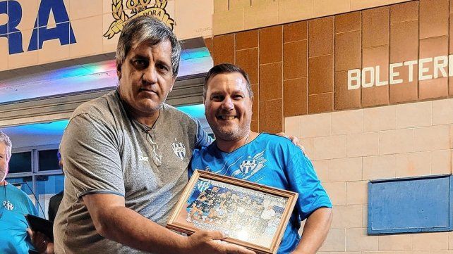 El presidente de Villa Dora, Adrián Ramseyer, entrega un presente al entrenador Mauricio Lozano.